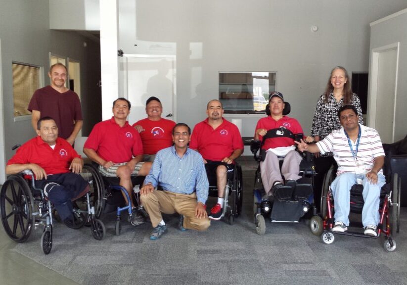 Group of people, some in wheelchairs, posing indoors.