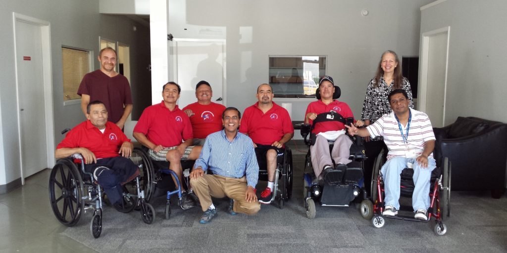 Group of people, some in wheelchairs, posing indoors.