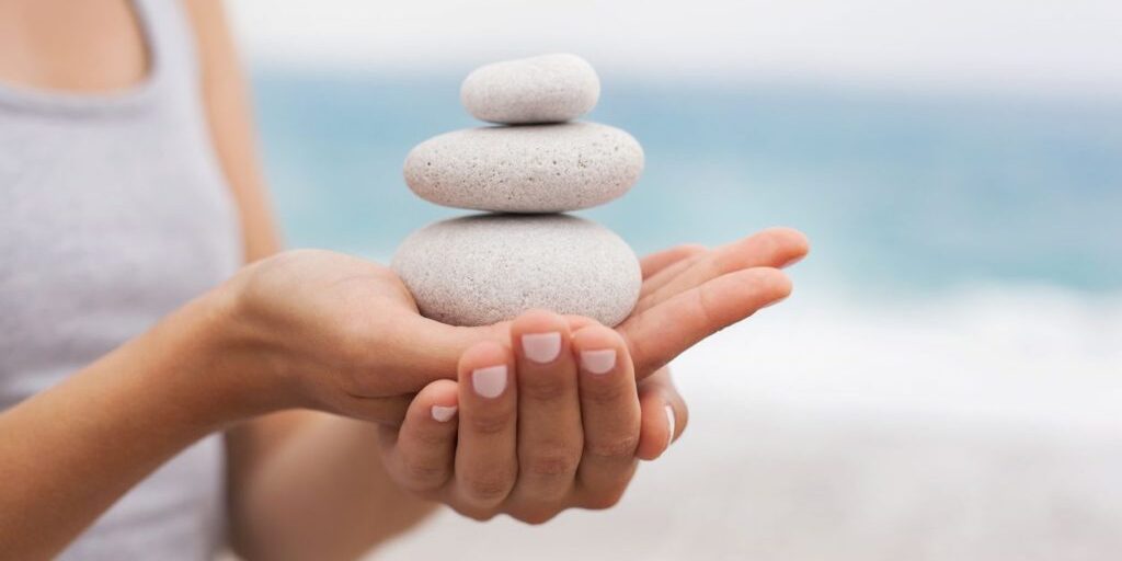 Stack of smooth stones balanced on a person's hand, symbolizing calm and balance.