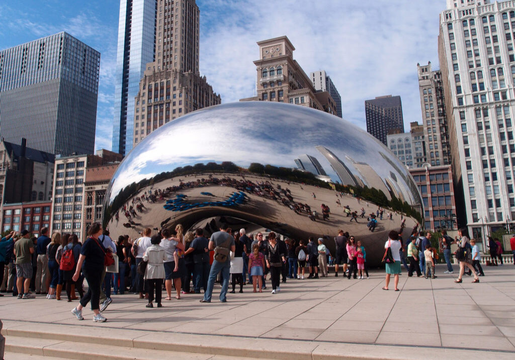 The Cloud Gate sculpture in Chicago filled with visitors on a sunny day.
