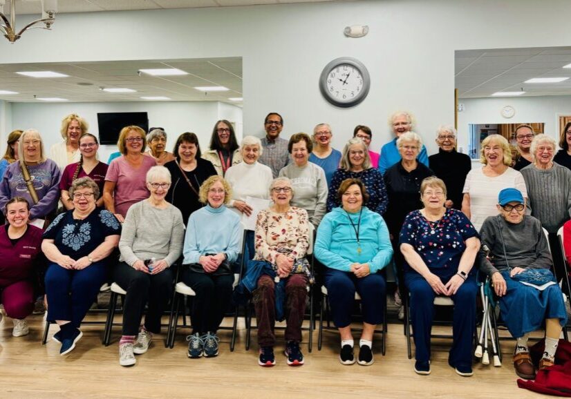 A group photo of elderly people gathered indoors, smiling.