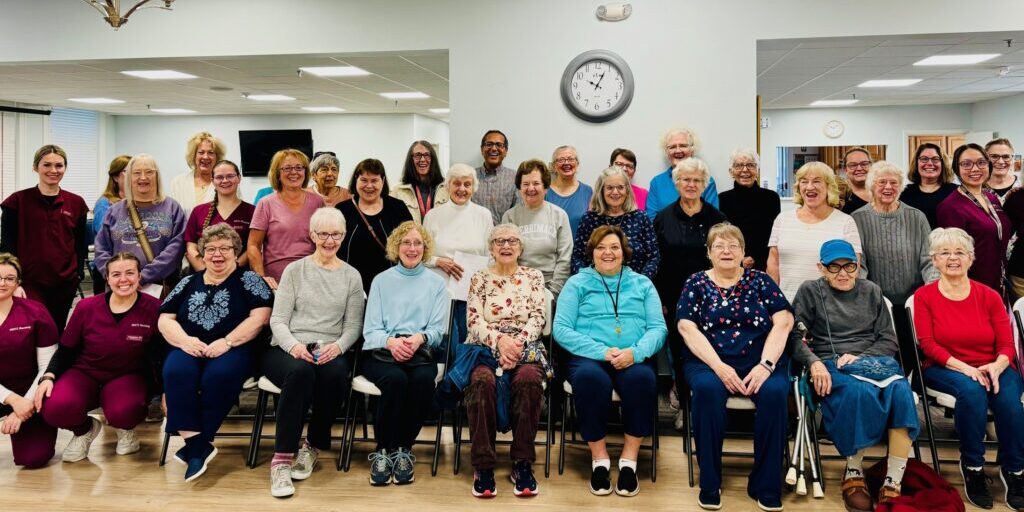 A group photo of elderly people gathered indoors, smiling.